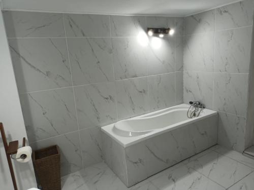 a white bath tub in a bathroom with marble walls at Pensiunea Deceneu in Slănic