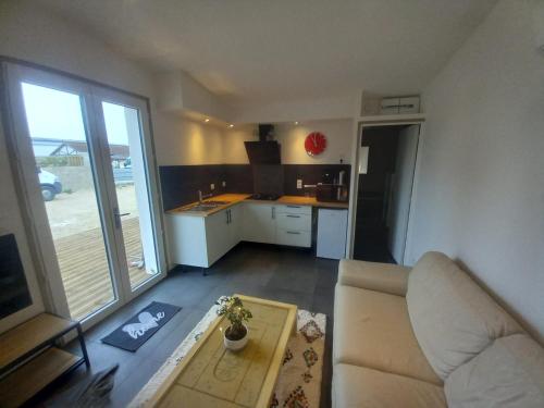 a living room with a couch and a kitchen at Une petite maison et sa prairie in Villefargeau