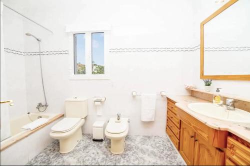 a white bathroom with a toilet and a sink at Villa with pool in Cala Blanca with sea views in Cala Santandria
