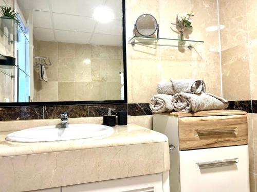 uma casa de banho com lavatório, espelho e toalhas em Apartment Sea Breeze – Apartamento Brisas del Mar em Benalmádena