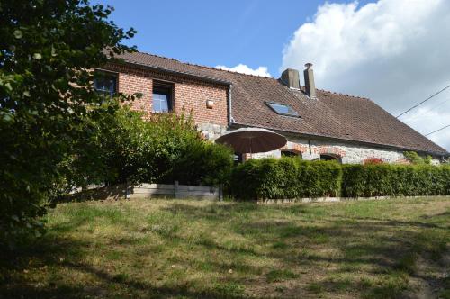 a brick house with an umbrella in the yard at Le Relais du Biau Ri en famille ou entre amis in Clairfayts