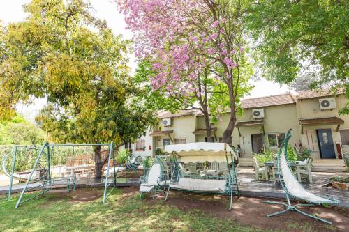 un patio con dos columpios y árboles y una casa en Nuriel Fruit & Guest House, en She'ar Yashuv