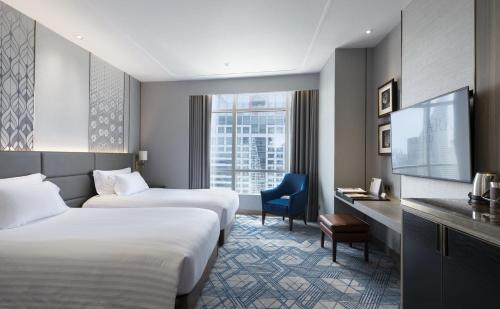 a hotel room with two beds and a tv at Centara Grand At CentralWorld in Bangkok