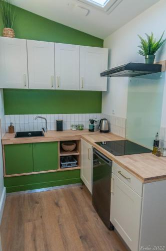 eine Küche mit grünen und weißen Schränken und einem Waschbecken in der Unterkunft Le T.Wood in La Gorgue
