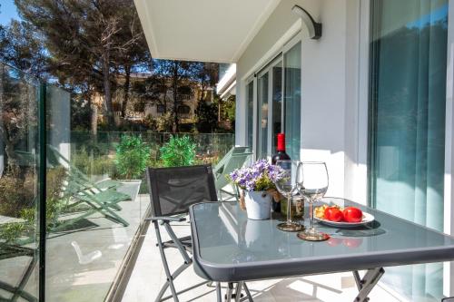 una mesa con copas de vino y flores en el balcón en Apartment 1B with pool , 150 meters Canyamel Beach, en Capdepera