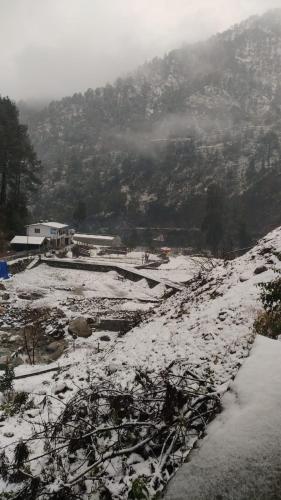 a snow covered field with a mountain in the background at Chirag Homestay Kainchi in Nainital