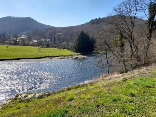 a river in a field next to a mountain at Chalet à L'orée du bois avec parking in Tournavaux
