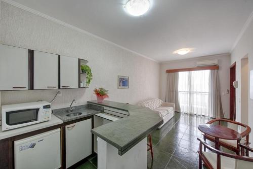eine Küche und ein Wohnzimmer mit einer Mikrowelle und einem Sofa in der Unterkunft Flat Itararé Tower Beach in São Vicente