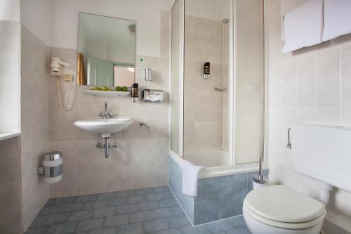 a bathroom with a toilet and a sink and a shower at INA Hotel Royal in Cologne