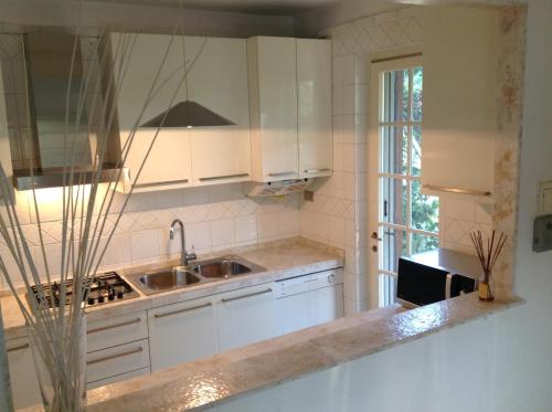 a kitchen with white cabinets and a sink at Holiday home Villetta Cinquale in Cinquale