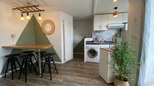 - une cuisine avec une table et quelques tabourets dans une pièce dans l'établissement RETOUR AUX SOURCES, à Royan