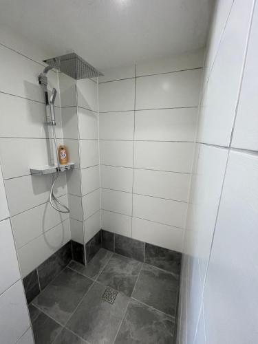 a bathroom with a shower with white tiles at Maharaja Ferienhaus in Hemfurth-Edersee