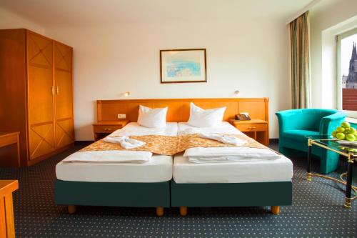 a hotel room with a bed and a blue chair at INA Hotel Royal in Cologne