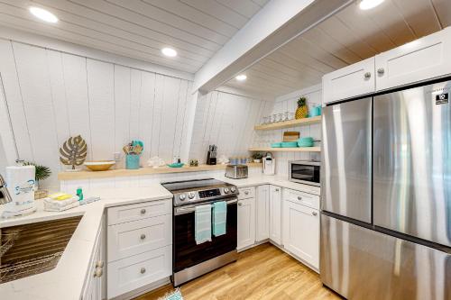 a kitchen with white cabinets and a stainless steel refrigerator at High Tide Hideaway in Dauphin Island