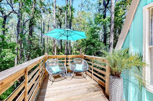 a deck with two chairs and an umbrella at High Tide Hideaway in Dauphin Island