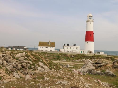 a red and white lighthouse sitting on top of a hill at Pebbles Reach in Portland