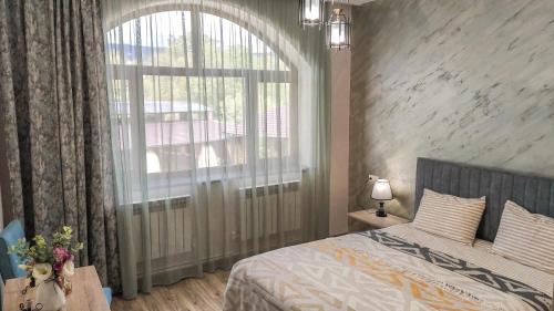 a bedroom with a bed and a large window at Harmonia Garden Hotel&Restaurant in Garni