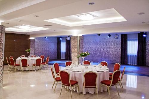 un salón de banquetes con mesas blancas y sillas rojas en Hotel Dunajec, en Zgłobice