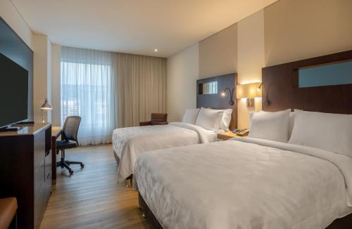 a hotel room with two beds and a flat screen tv at Holiday Inn Bogota Airport by IHG in Bogotá