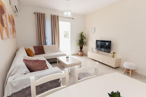 a white living room with a couch and a tv at CAPTAIN'S RESIDENCE in Ksamil