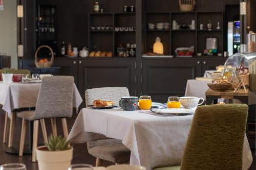 un comedor con 2 mesas con platos de comida en Logis Hôtel Tante Yvonne & son restaurant semi-gastronomique - Lyon Nord, en Quincieux