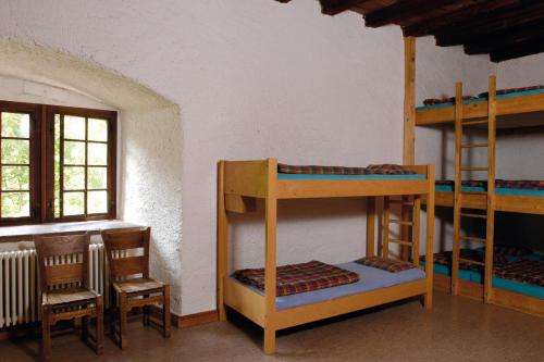 Habitación con literas, mesa y sillas. en Mariastein-Rotberg Youth Hostel en Mariastein