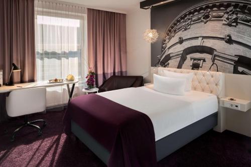 um quarto de hotel com uma cama grande e uma secretária em Dorint Kongresshotel Mannheim em Mannheim