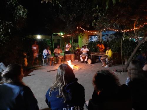 um grupo de pessoas sentadas à volta de uma fogueira à noite em Franco Inn Guesthouse em Tanji