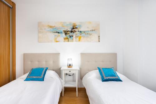 2 łóżka w białym pokoju z niebieskimi poduszkami w obiekcie Home2Book Stunning Santa Cruz City Views w mieście Santa Cruz de Tenerife