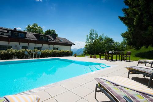 a large swimming pool with chairs and a house at Romantikhotel Die Gersberg Alm in Salzburg