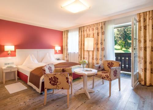 a hotel room with a bed and a table and chairs at Romantikhotel Die Gersberg Alm in Salzburg