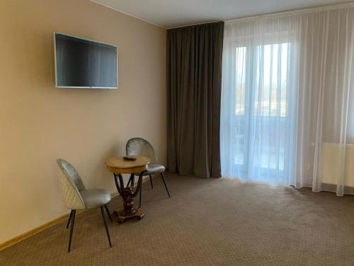 a room with two chairs and a table and a television at Hotel Baltazar Pułtusk in Pultusk