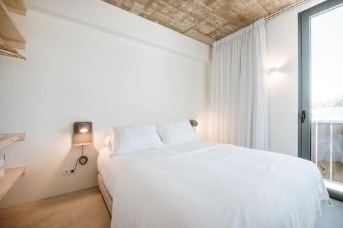 a bedroom with a white bed and a window at B.Hostel in Comporta