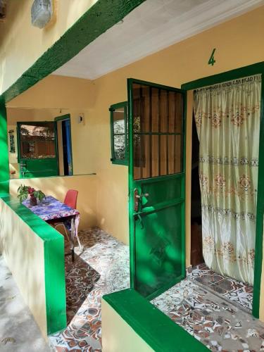 a green door in a room with a table at Franco Inn Guesthouse in Tanji