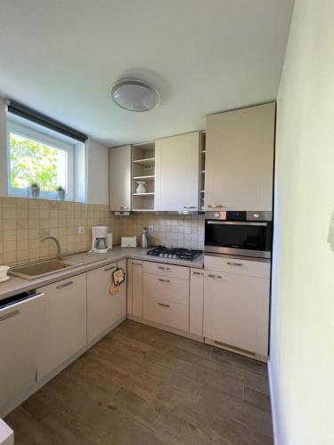 a kitchen with white cabinets and a sink and a window at AL-DOM Apartamenty Apartament Zaciszny in Kołobrzeg