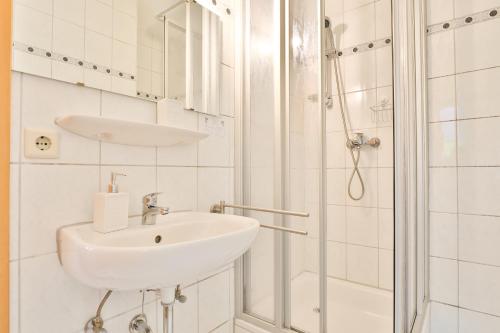 a white bathroom with a sink and a shower at Hotel JUMAs in Bad Zwischenahn