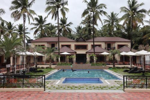 a resort with a swimming pool and palm trees at Royal Destiny Resort in Malaiyāndipattanam