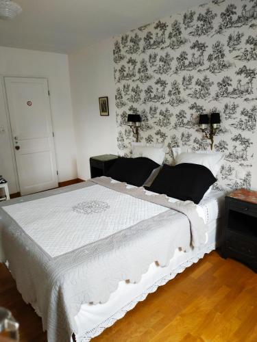 1 dormitorio con cama blanca y papel pintado con motivos florales en La loge, en Menetou-Salon