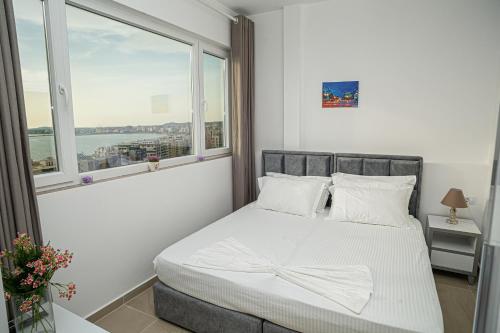 a bedroom with a bed with white sheets and a window at Hotel SUNSET GL in Vlorë