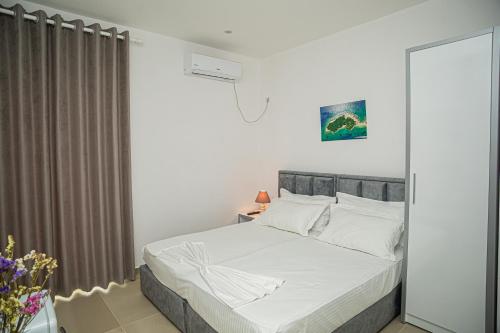 a white bedroom with a bed and a window at Hotel SUNSET GL in Vlorë