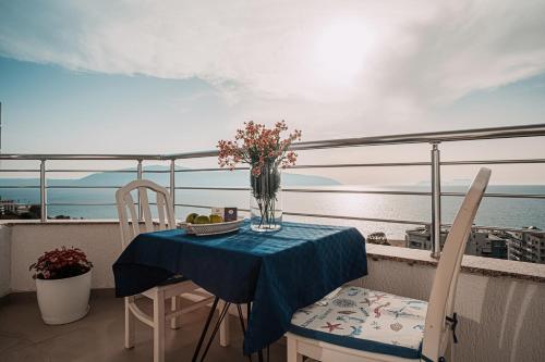 a table with chairs and a vase of flowers on a balcony at Hotel SUNSET GL in Vlorë