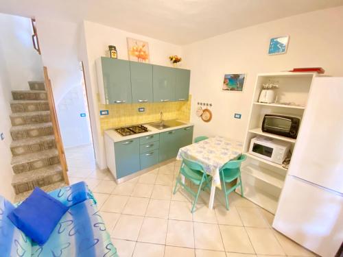 una cucina con armadi blu, tavolo e forno a microonde di Appartamento Via Trentino a San Teodoro