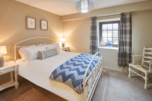 1 dormitorio con cama blanca y ventana en Beadnell Bay Cottage, en Beadnell