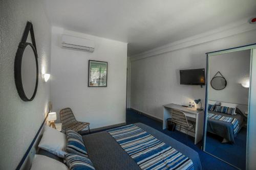 ein Hotelzimmer mit einem Bett und einem Spiegel in der Unterkunft Le Fanal in Argelès-sur-Mer