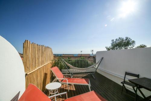 eine Terrasse mit Stühlen und einer Hängematte auf dem Balkon in der Unterkunft Le Fanal in Argelès-sur-Mer