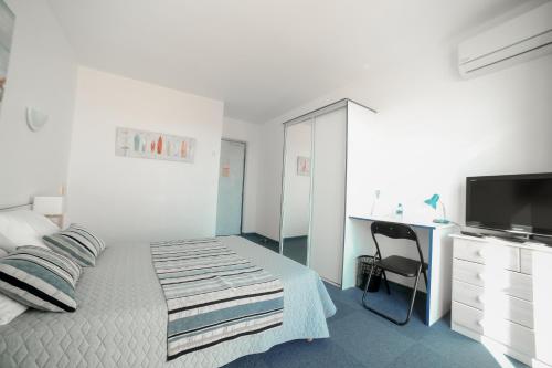 a bedroom with a bed and a desk and a television at Le Fanal in Argelès-sur-Mer
