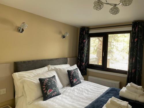 a bedroom with a bed with pillows and a window at Luxury Riverside Lodge, Blair Atholl in Pitlochry