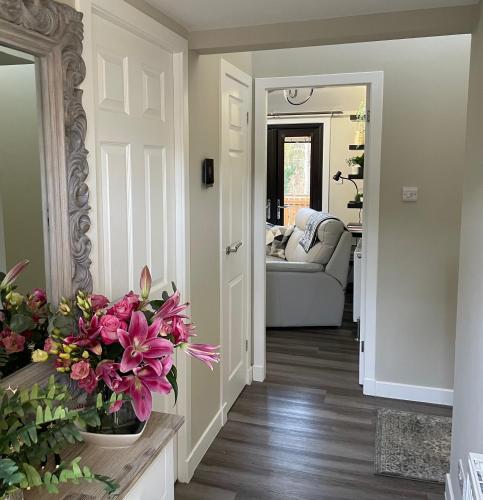 a hallway with a living room with a couch and flowers at Luxury Riverside Lodge, Blair Atholl in Pitlochry