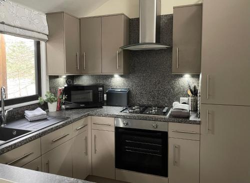 a kitchen with white cabinets and a stove top oven at Luxury Riverside Lodge, Blair Atholl in Pitlochry
