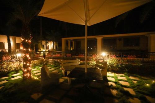 a patio with an umbrella and two benches at night at Royal Destiny Resort in Malaiyāndipattanam